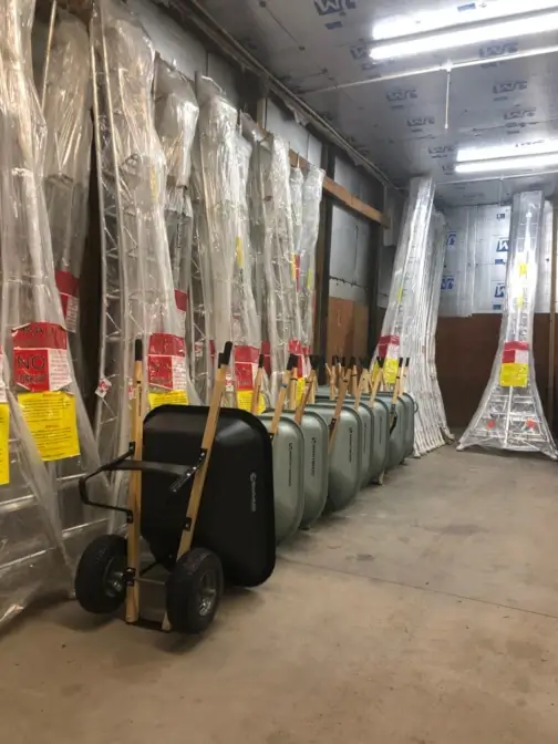 Row of packaged ladders and wheelbarrows in storage